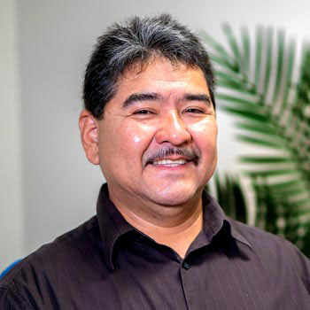 Felipe Zuniga smiling for a picture in front of a plant
