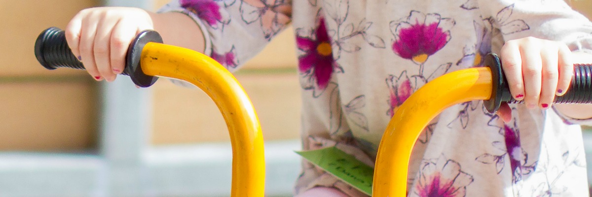 Child's hands on tricycle handle bars